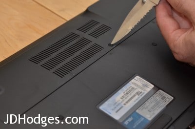Gently pry the adhesive screw cover off the with a blade/pen or similar object