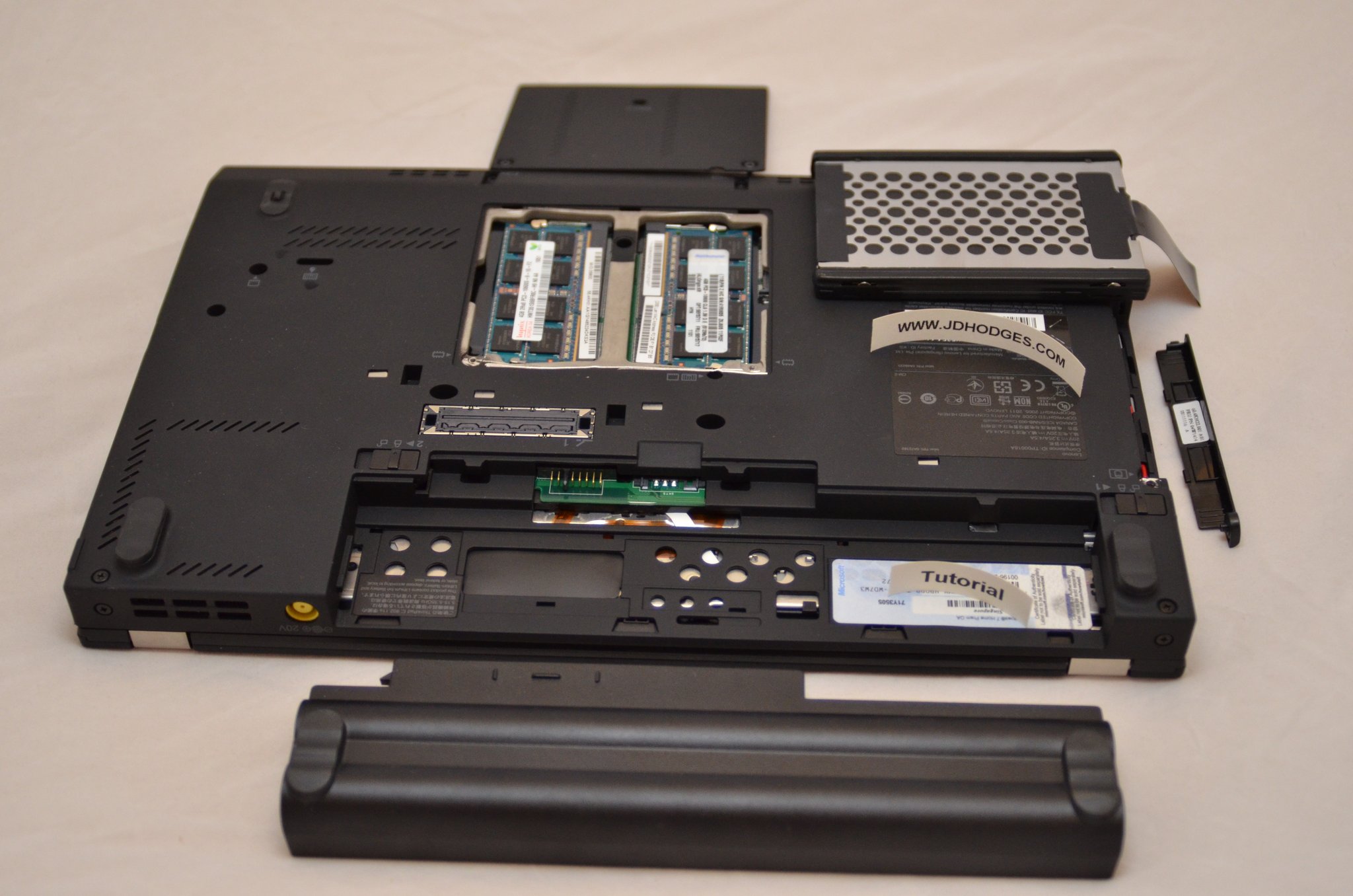 X220 with main battery, palm-rest CMOS battery, 2.5-inch HDD caddy, two SODIMMs, and a docking-port cover laid out on a neutral background.